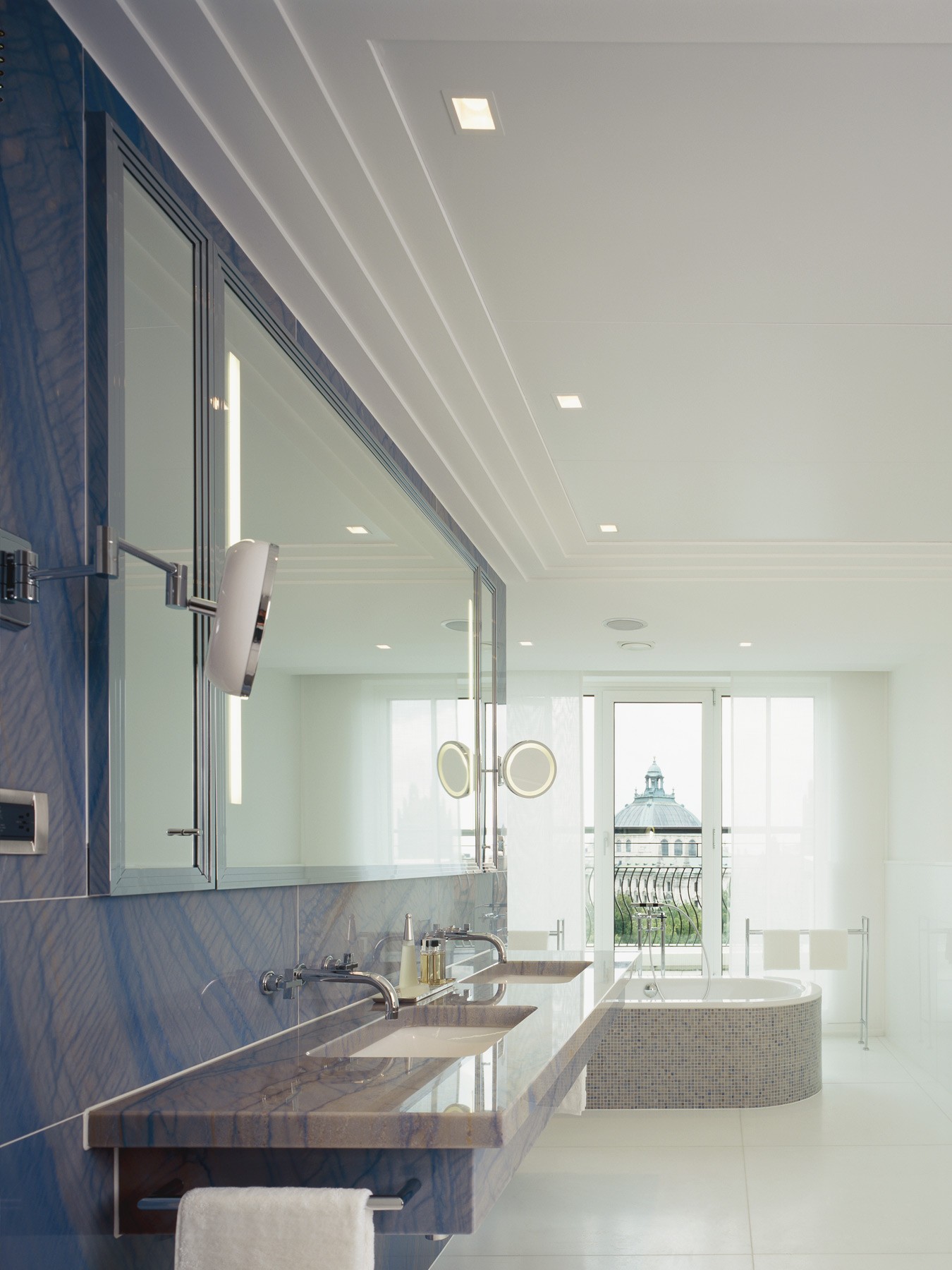 Badezimmer mit hochwertigen Steinfliesen und Ausblick im exklusiven Wohnquartier Lenbach Gärten in München