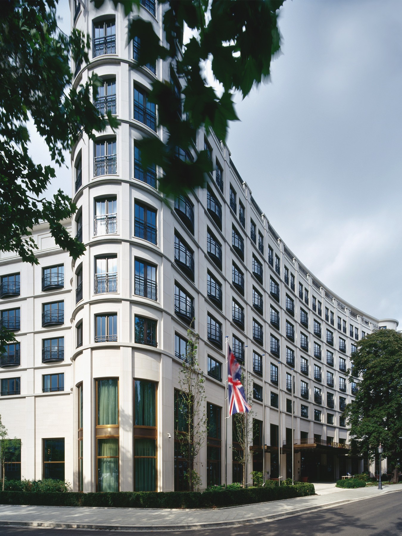 Fassade des Charles Hotels mit Bäumen und englischer Flagge im Quartier Lenbach Gärten in München