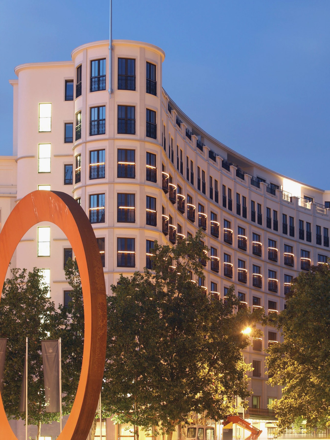 Nachts beleuchtete Fassade des Charles Hotels mit Kunstwerk im Vordergrund in den Lenbach Gärten in München