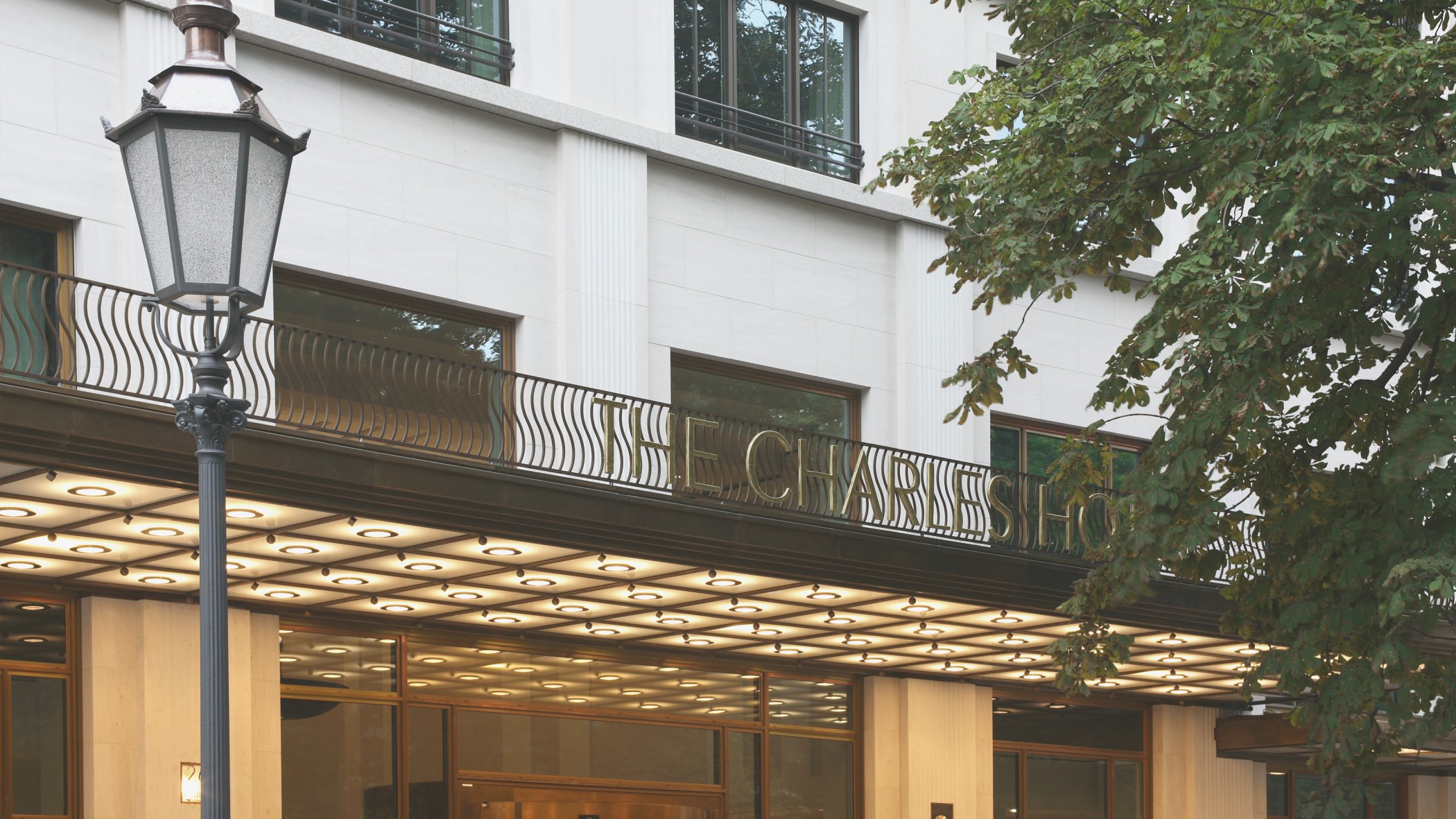 Nahaufnahme des Schriftzuges über dem Eingangsbereich des Charles Hotels mit klassischer Laterne im exklusiven Wohnquartier Lenbach Gärten München