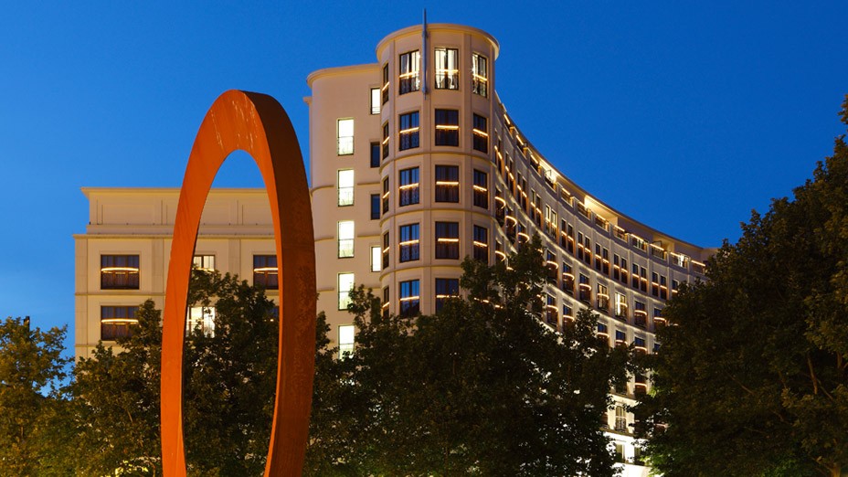 Nachts beleuchtete Fassade des Charles Hotels mit Kunstwerk im Vordergrund in den Lenbach Gärten in München