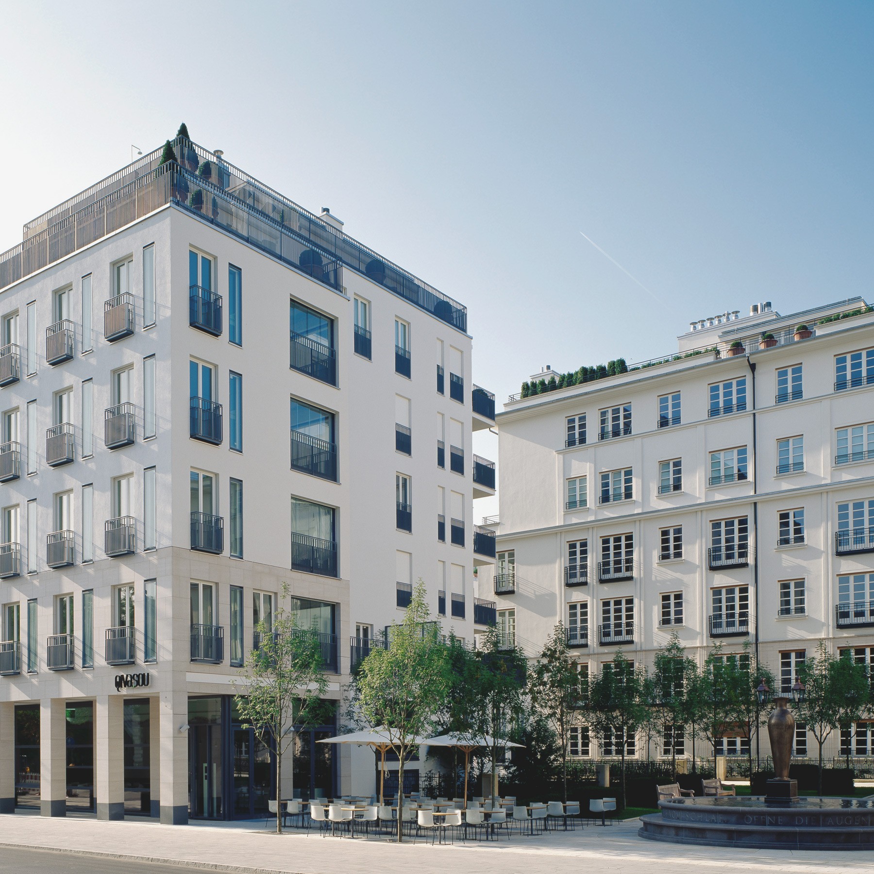Moderne klassische Architektur mit ausblick auf den Platz mit Café und Brunnen im Wohnquartier Lenbach Gärten in München
