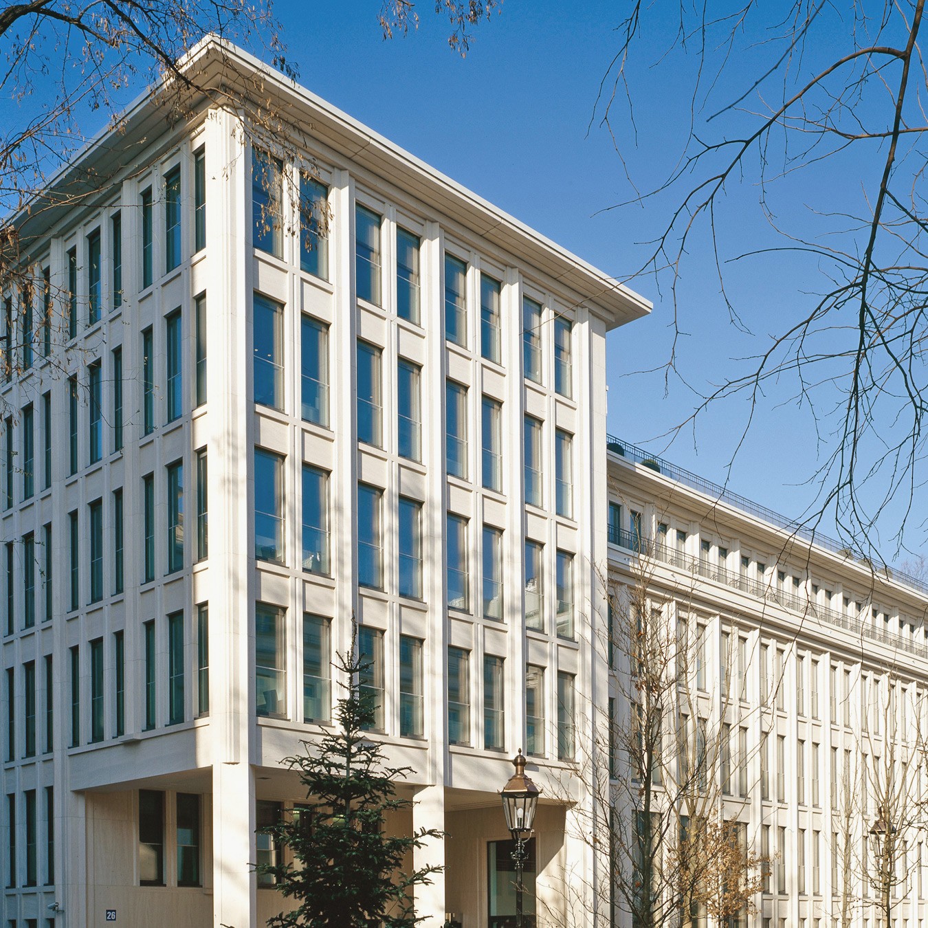 Fassade des Bürogebäudes mit Bäumen im Voerdergrund bei sonnenschein in den Lenbach Gärten in München