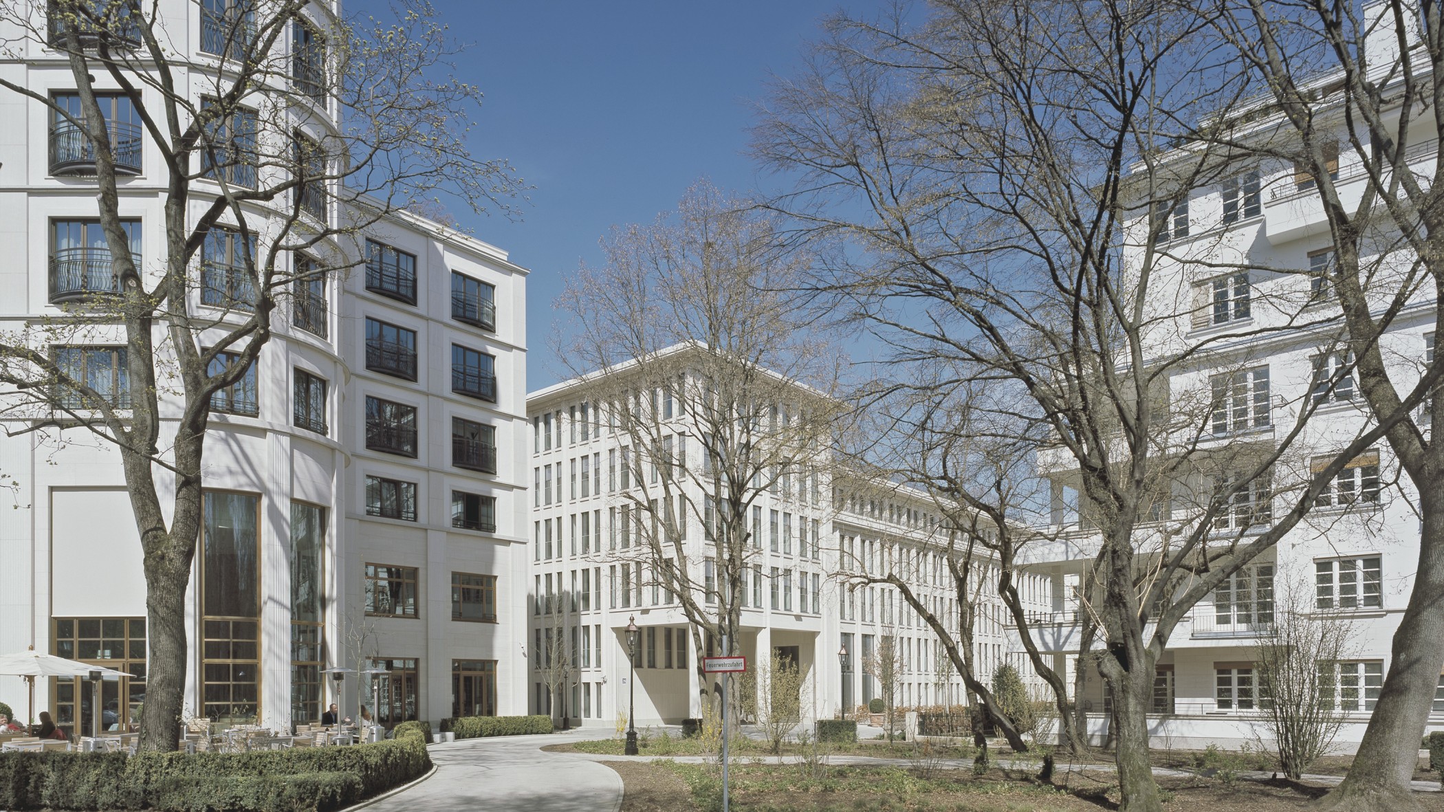 Blick vom Charles Hotel zum Bürogebäude durch die Grünanlage im Wohnquartier Lenbach Gärten in München